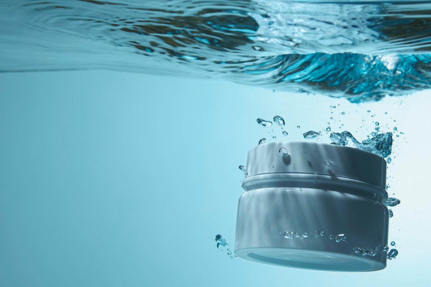 Cosmétique marine : quels bienfaits pour la peau ? 1 Un pot de creme est plongé dans l'eau afin d'illustrer les cosmétiques aux ingrédients marins.